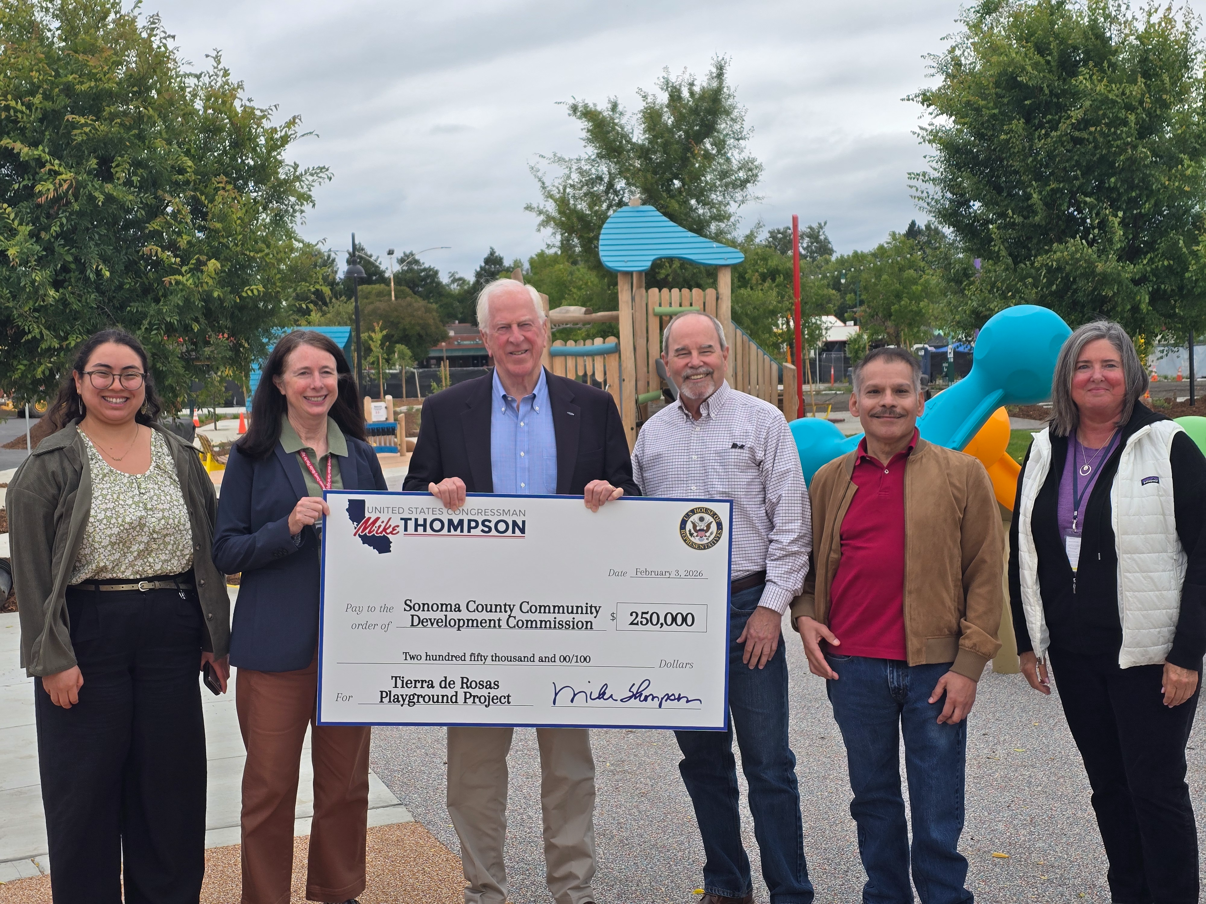 Group Photo with Rep. Thompson Holding a Check in Front of Playground